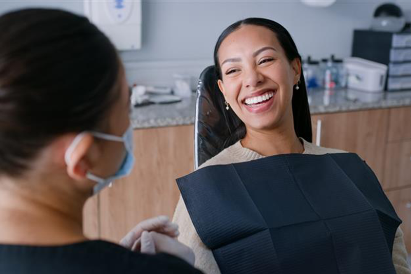 Patient in exam chair at dentist office smiles at hygienist