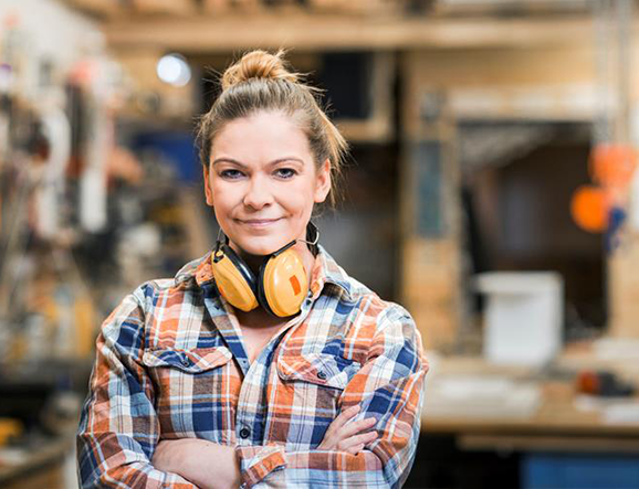 Smiling carpenter wearing noise-reduction headphones around neck