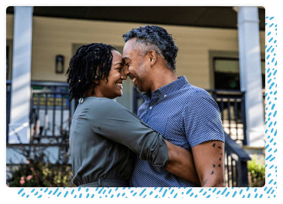 a couple embraces in front of a house