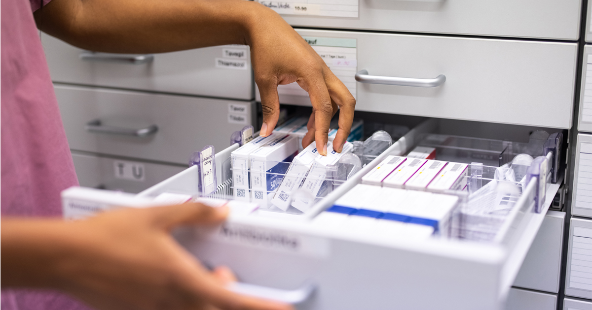 A person searches through a drawer full of medication boxes