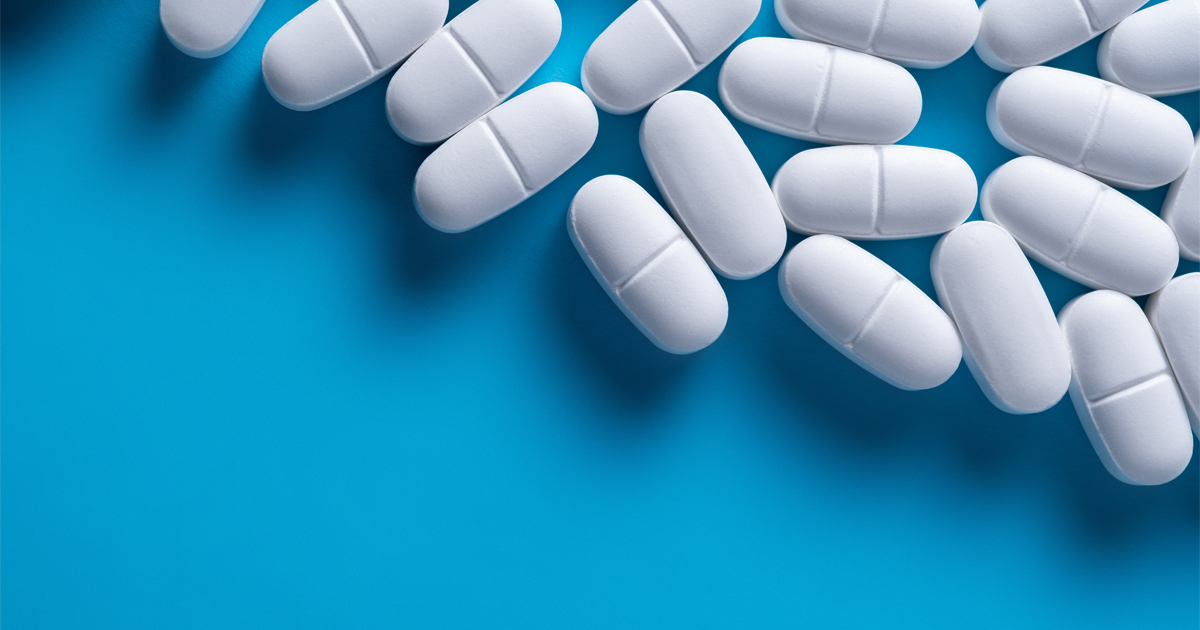 Twenty white medicine tablets on a blue background