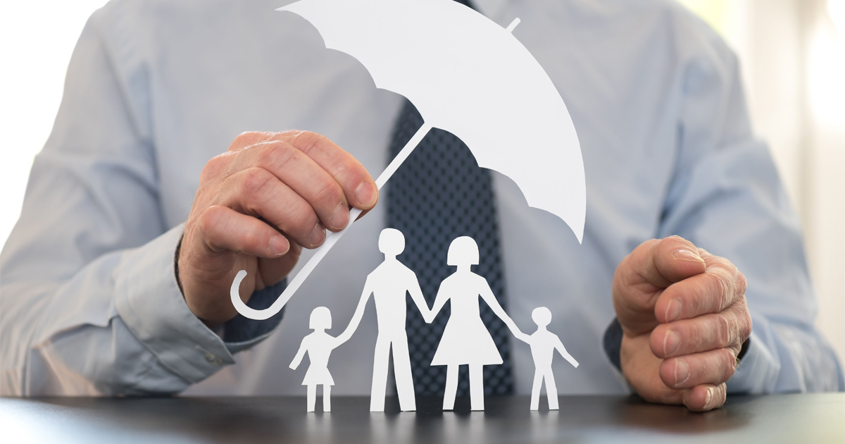 A man holds a cut-out paper umbrella over a cut-out paper doll family