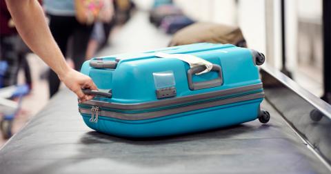 A person collects a blue suitcase from a baggage claim conveyor belt.