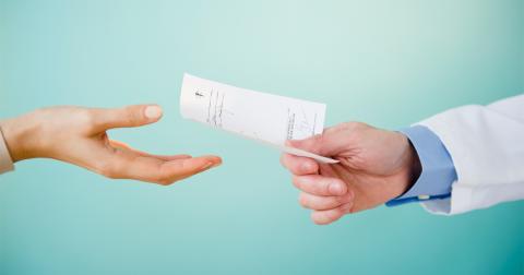 A doctor hands a paper prescription to a patient