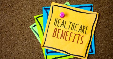 A stack of colorful notes is pinned to a bulletin board. The note on top reads 'Healthcare Benefits'.